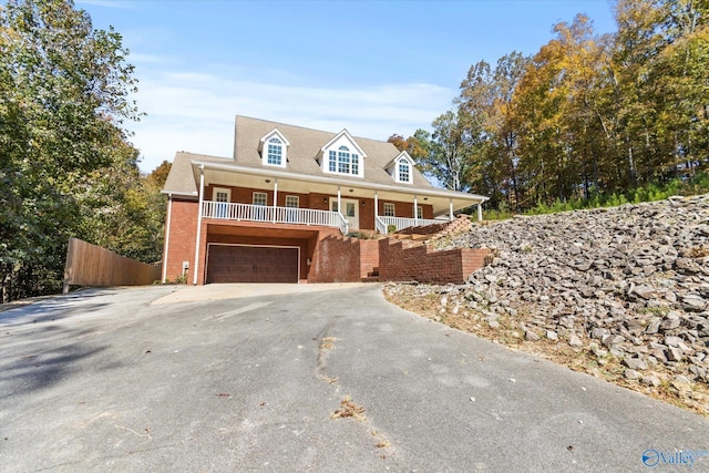 new england style home with covered porch and a garage