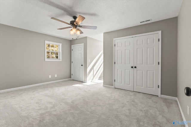 unfurnished bedroom with a textured ceiling, light colored carpet, and ceiling fan