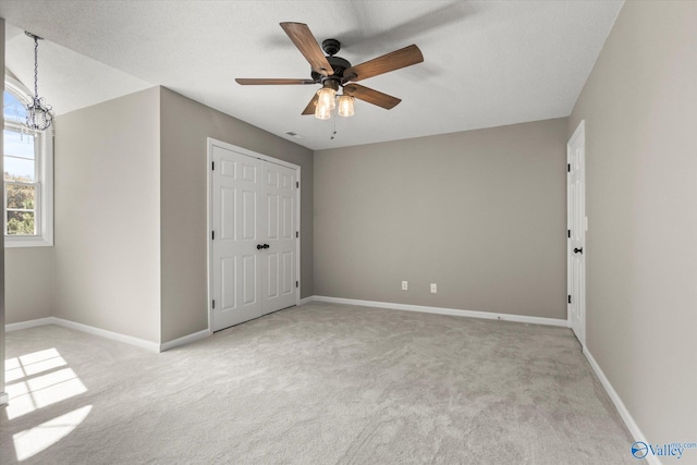 unfurnished bedroom featuring a closet, ceiling fan, light carpet, and a textured ceiling