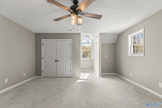 unfurnished bedroom with light carpet, a closet, a textured ceiling, and ceiling fan