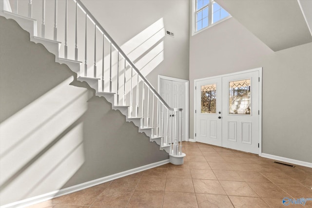 foyer entrance featuring french doors, a high ceiling, and light tile patterned floors