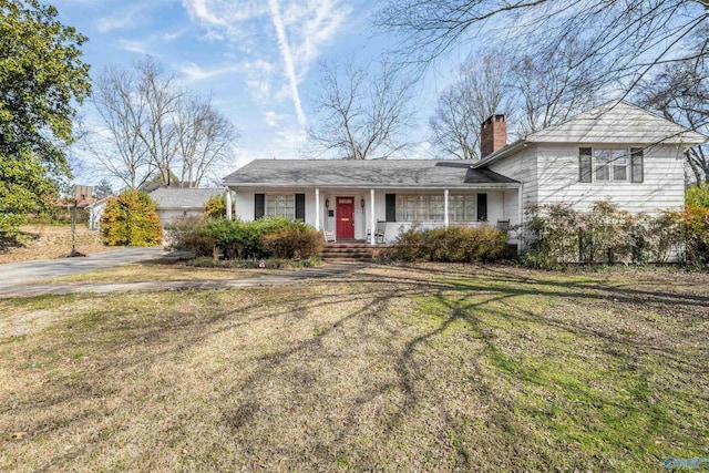 split level home with covered porch, a chimney, and a front yard