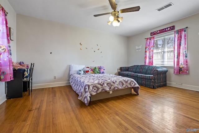 bedroom with hardwood / wood-style floors, a ceiling fan, visible vents, and baseboards