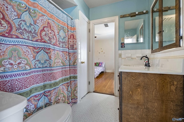 ensuite bathroom featuring tasteful backsplash, a shower with shower curtain, toilet, connected bathroom, and vanity