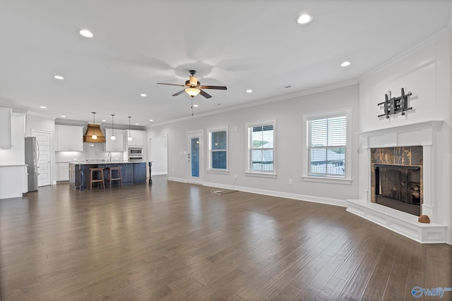 unfurnished living room featuring sink, ceiling fan, crown molding, and dark hardwood / wood-style flooring