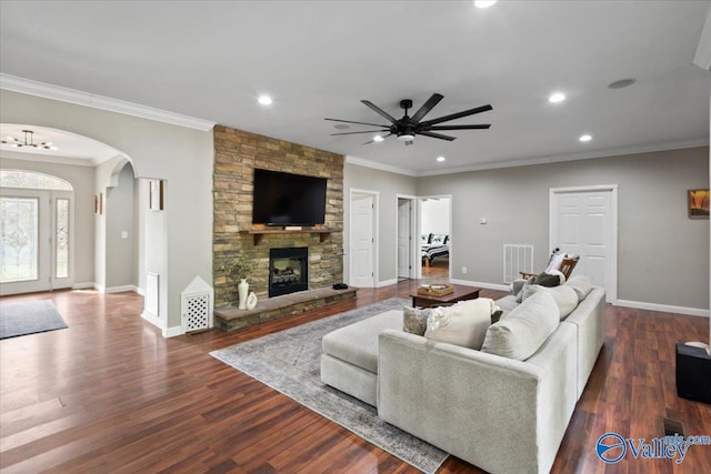 living room featuring a fireplace, dark wood-type flooring, ceiling fan, and crown molding