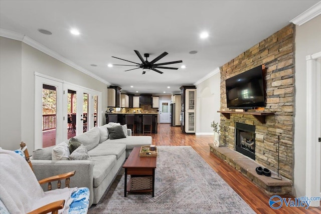 living room with dark wood-type flooring, a fireplace, and crown molding