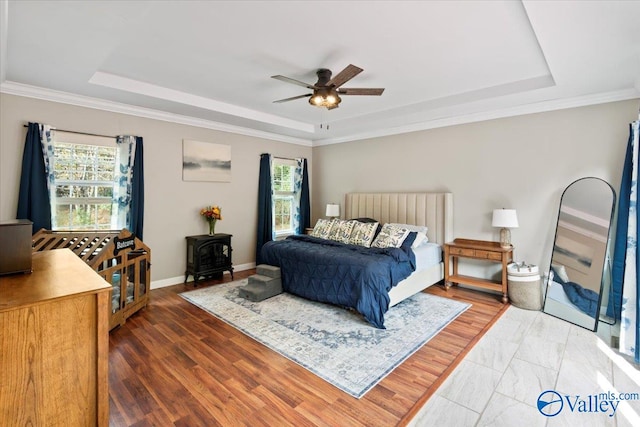 bedroom with ceiling fan, multiple windows, and a raised ceiling