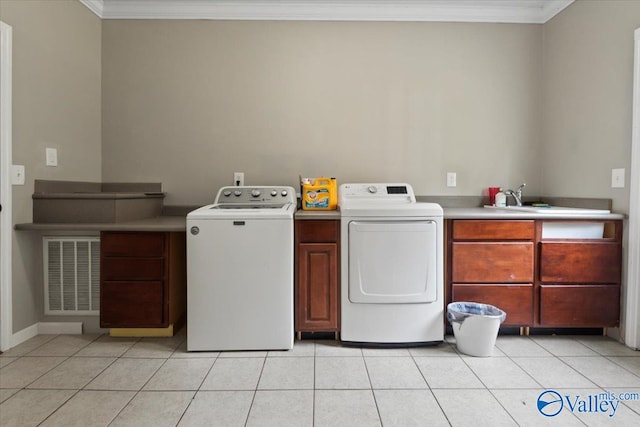 laundry area with light tile patterned flooring, crown molding, cabinets, sink, and washer and dryer