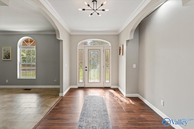 foyer featuring dark hardwood / wood-style flooring, a notable chandelier, and crown molding