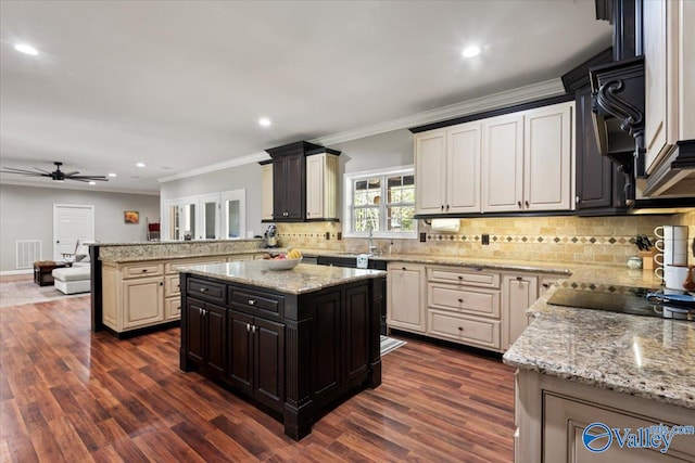 kitchen with ornamental molding, light stone counters, dark hardwood / wood-style floors, and a center island