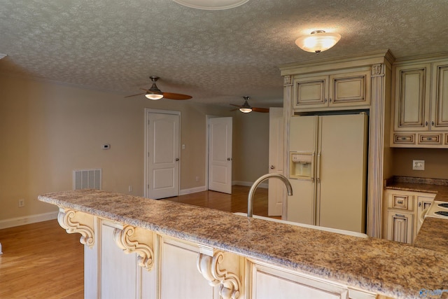 kitchen with light hardwood / wood-style flooring, white refrigerator with ice dispenser, a textured ceiling, and ceiling fan