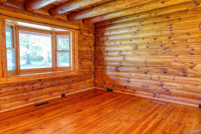 unfurnished room featuring beamed ceiling, wood walls, wood ceiling, and light hardwood / wood-style flooring
