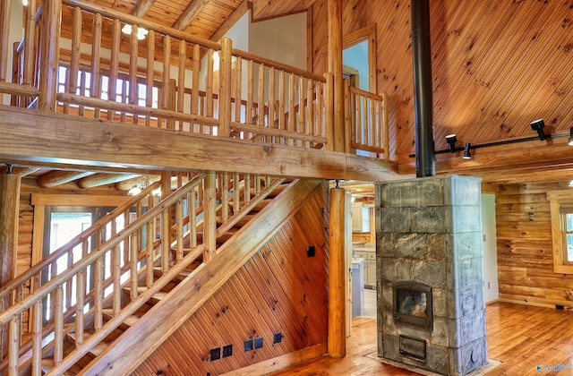 stairway featuring high vaulted ceiling, wooden ceiling, hardwood / wood-style floors, and a wood stove