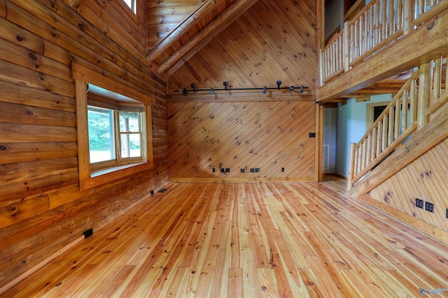 interior space with hardwood / wood-style flooring, wood walls, and a high ceiling