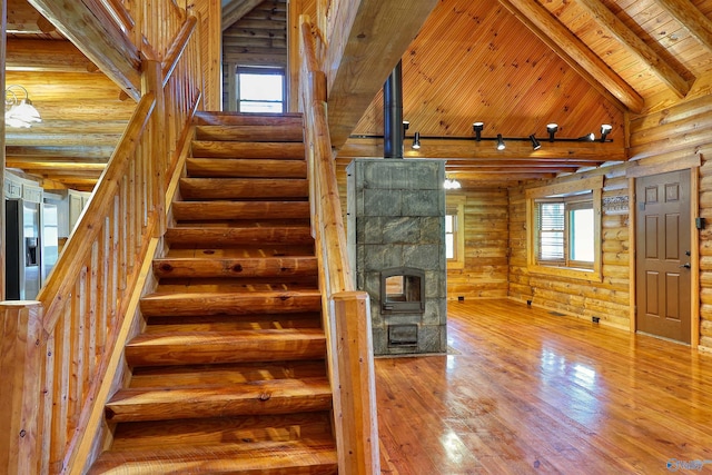 staircase featuring hardwood / wood-style floors, beamed ceiling, rustic walls, track lighting, and wooden ceiling