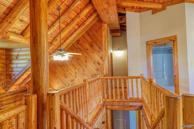 stairs with log walls, wood ceiling, and beamed ceiling