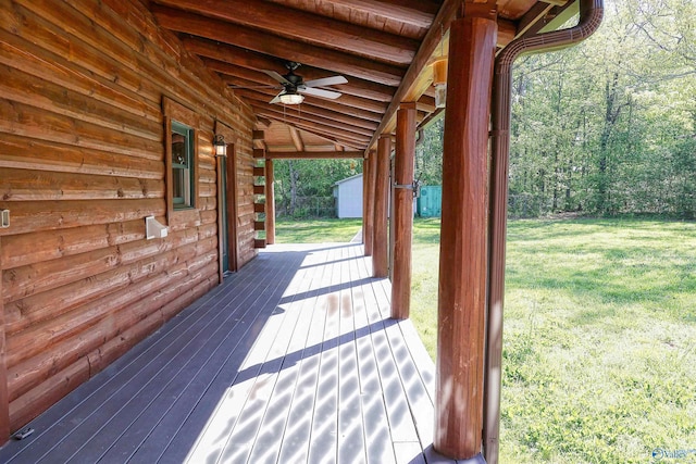 deck featuring a storage unit, ceiling fan, and a lawn