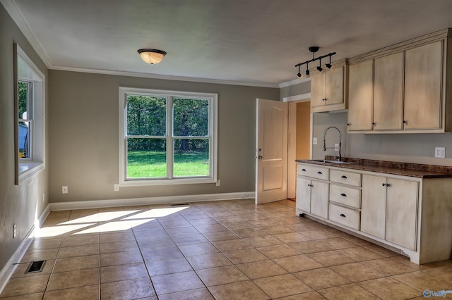 kitchen with light brown cabinetry, sink, light tile patterned flooring, and crown molding