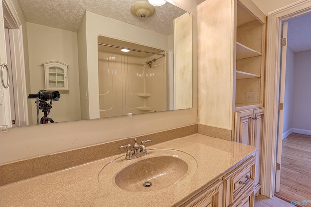 bathroom with vanity, a textured ceiling, and walk in shower