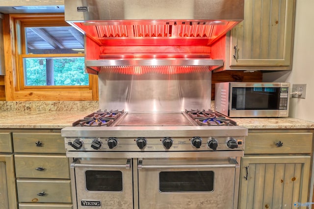 kitchen with custom range hood, light stone counters, and stainless steel appliances