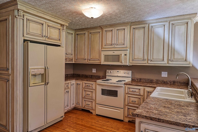 kitchen featuring sink, a textured ceiling, hardwood / wood-style flooring, and white appliances