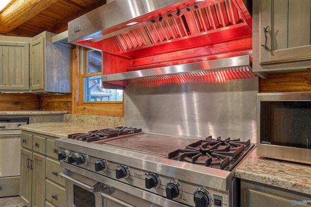 kitchen featuring appliances with stainless steel finishes, wall chimney range hood, and light stone counters