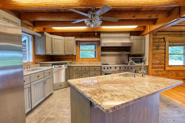 kitchen with ceiling fan, stainless steel appliances, wall chimney exhaust hood, sink, and beam ceiling