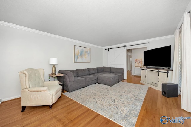 living room with ornamental molding, a barn door, and hardwood / wood-style floors