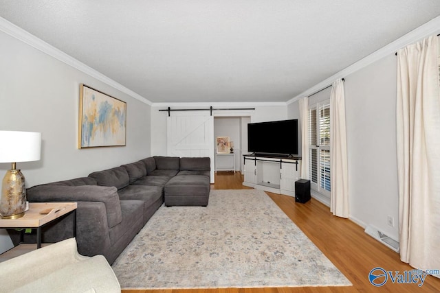 living room with hardwood / wood-style flooring, a barn door, and crown molding