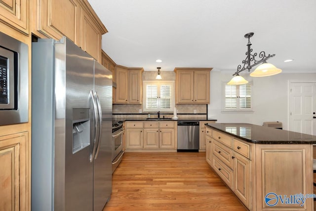 kitchen with stainless steel appliances, sink, a center island, and light brown cabinets