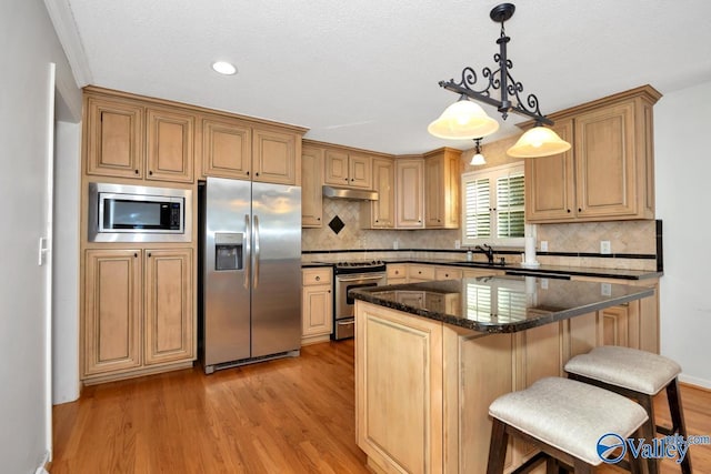 kitchen featuring sink, decorative light fixtures, light wood-type flooring, a kitchen island, and stainless steel appliances