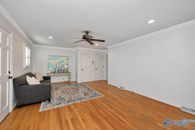 sitting room with ornamental molding, a textured ceiling, and light hardwood / wood-style flooring