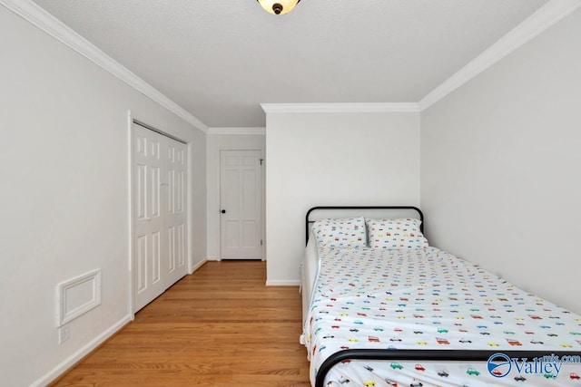 bedroom featuring ornamental molding, a closet, a textured ceiling, and light wood-type flooring