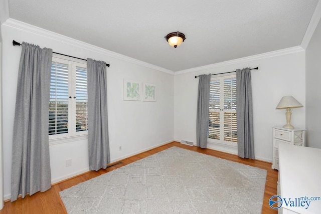 spare room featuring ornamental molding and light wood-type flooring