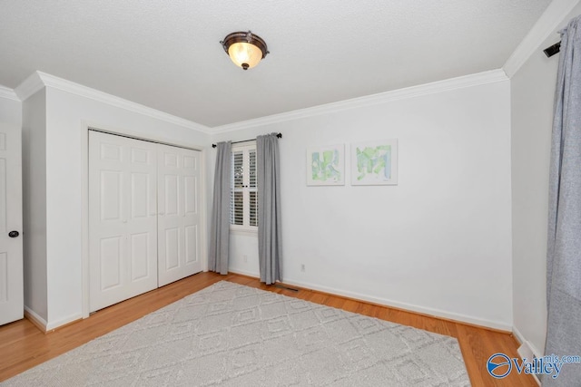 bedroom featuring hardwood / wood-style floors, ornamental molding, and a closet