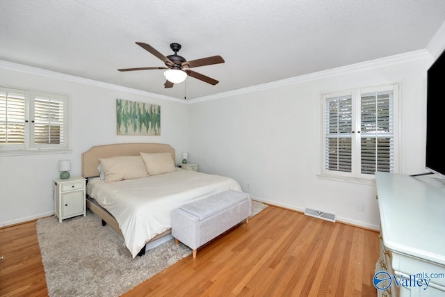 bedroom with multiple windows, ornamental molding, hardwood / wood-style floors, and a textured ceiling