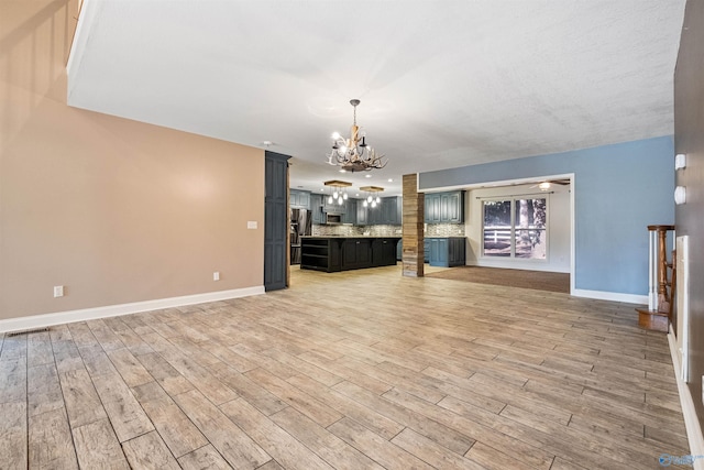 unfurnished living room featuring a notable chandelier and light hardwood / wood-style floors