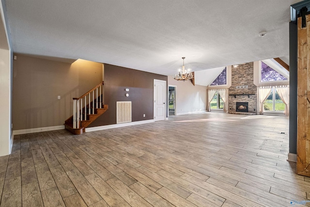 unfurnished living room with an inviting chandelier, a stone fireplace, light wood-type flooring, and vaulted ceiling