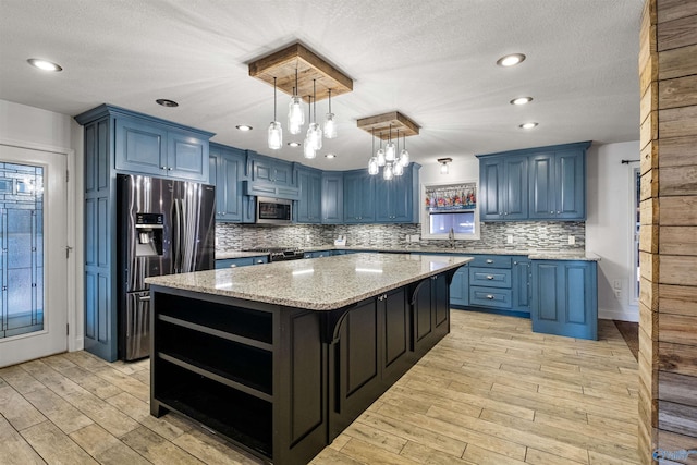 kitchen featuring light stone countertops, a notable chandelier, decorative light fixtures, a kitchen island, and appliances with stainless steel finishes