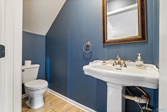 bathroom with toilet, wood-type flooring, and vaulted ceiling