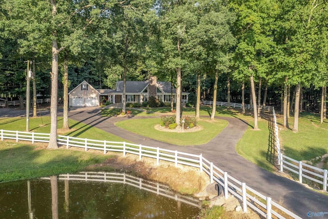 view of front of house featuring a rural view, a front yard, a garage, an outbuilding, and a water view