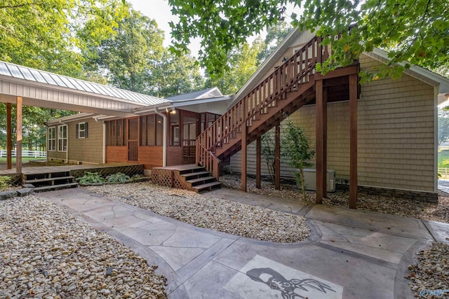 rear view of house featuring central AC, a deck, and a sunroom