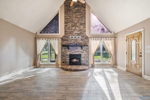 unfurnished living room with a fireplace, high vaulted ceiling, a wealth of natural light, and ceiling fan