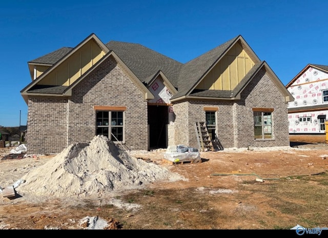 craftsman inspired home featuring roof with shingles, board and batten siding, and brick siding