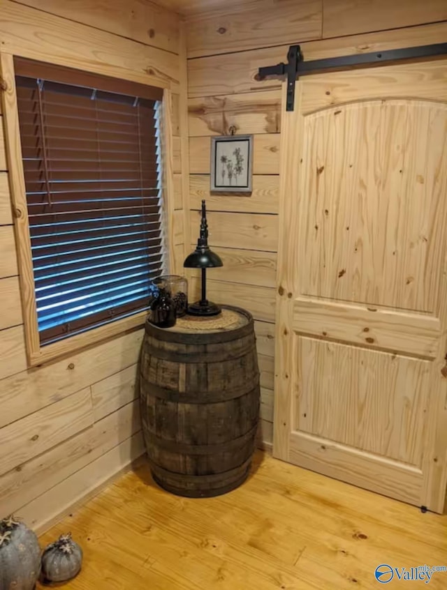 room details featuring hardwood / wood-style flooring, a barn door, and wood walls