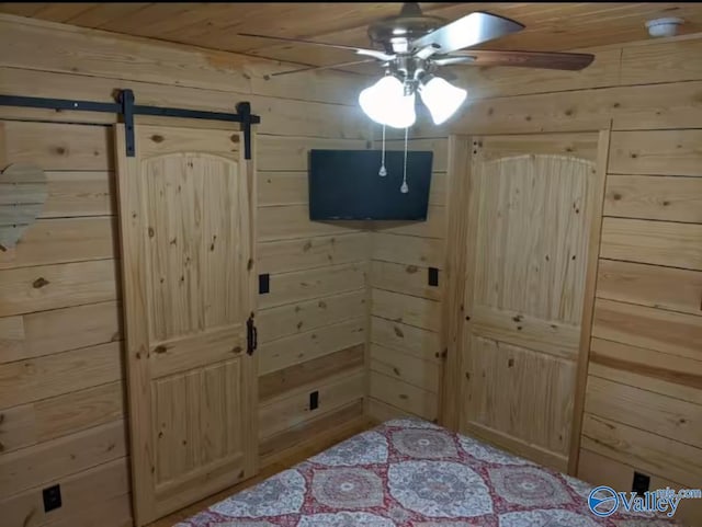 bedroom featuring a barn door, wooden ceiling, and wood walls