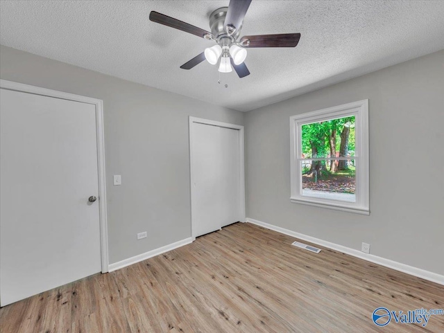 1419 11th St SE, Cullman, AL 35055 - unfurnished bedroom with a textured ceiling, visible vents, wood finished floors, baseboards, and a closet