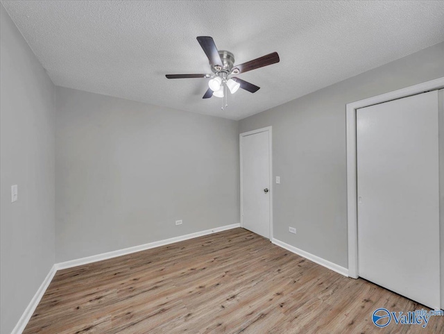 1419 11th St SE, Cullman, AL 35055 - unfurnished bedroom with a textured ceiling, baseboards, a ceiling fan, and wood finished floors