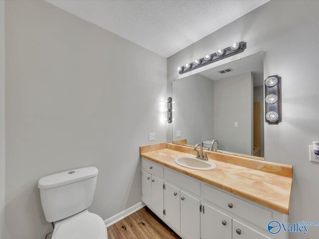 1419 11th St SE, Cullman, AL 35055 - bathroom featuring vanity, toilet, baseboards, wood finished floors, and visible vents
